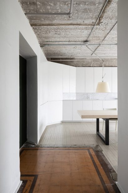 Entrance to meeting room with aged brown tiles, exposed concrete ceiling and white cabinetry in D'Arcy Jones Architects studio
