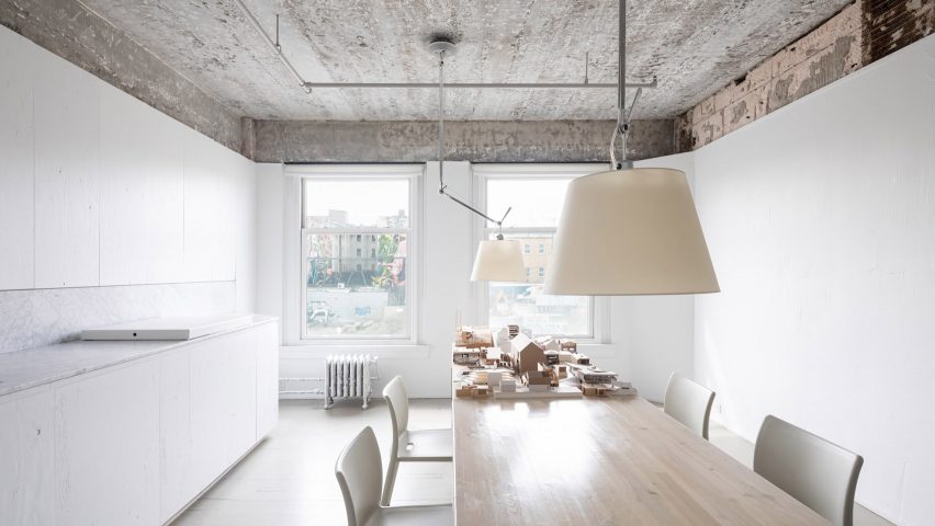 Meeting room with light wooden table, white cabinetry and exposed concrete ceiling in Vancouver architecture studio