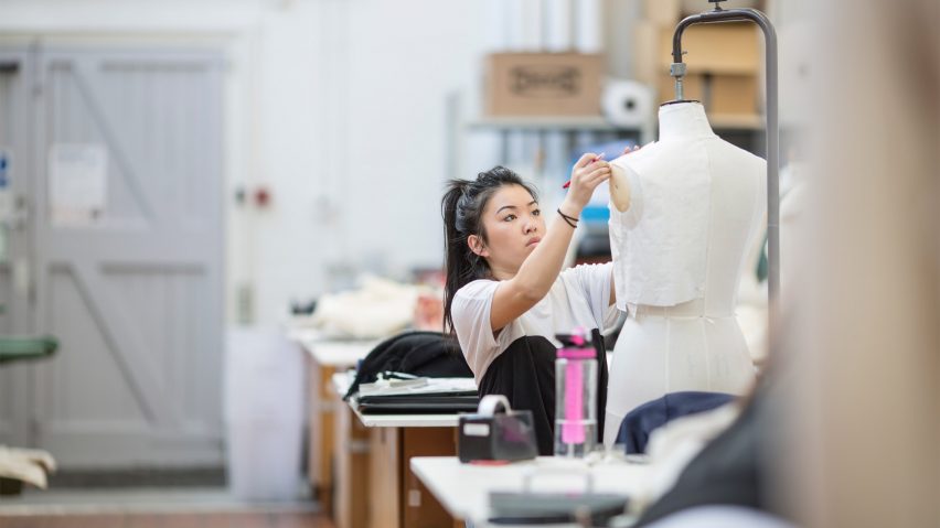 A photograph of a student pinning fabric to a dressmaker's' mannequin