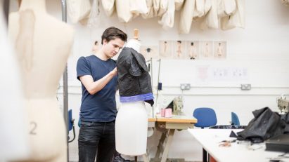 A photograoh of a student pinning fabric to a dressmakers' mannequin