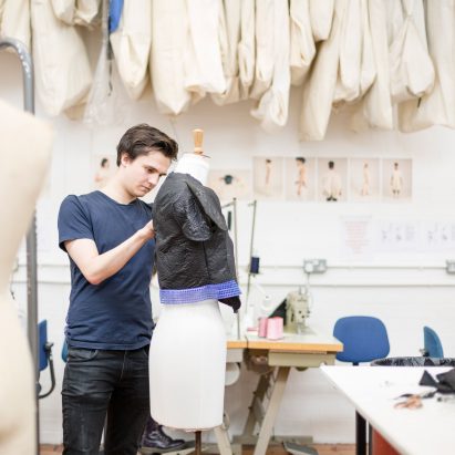 A photograoh of a student pinning fabric to a dressmakers' mannequin