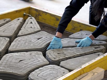 Hand placing 3D-printed mineral foam formwork inside timber perimeter formwork for concrete casting