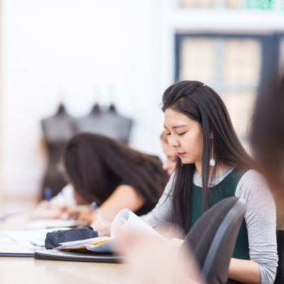 A photograph of a Global Fashion Management student studying at a desk