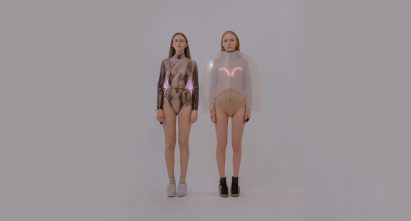 Two models stand next to each other wearing tops with LED lights