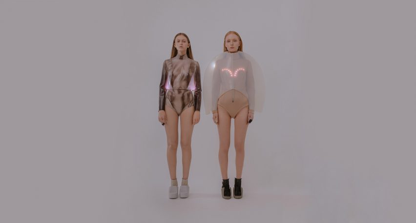 Two models stand next to each other wearing tops with LED lights