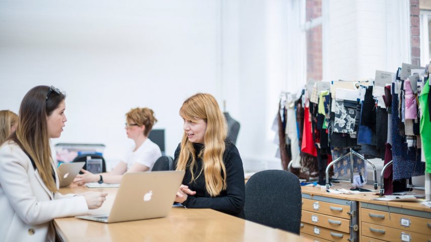 Students sit around a work bench in a studio