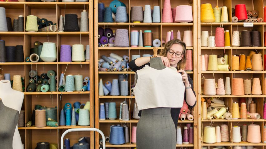 Student dressing a mannequin infront of shelving