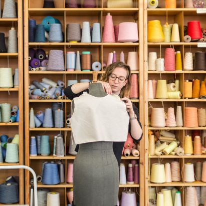 Student dressing a mannequin infront of shelving