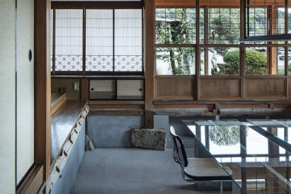 Rattan office chair in front of glass table inside office by DDAA Inc in a converted Japanese house