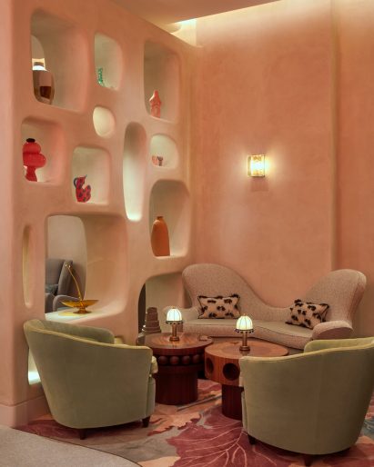 Seating nook in The Connaught hotel bar with green armchairs and curved beige sofa