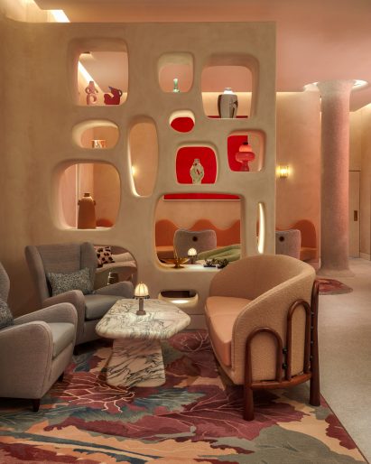 Seating area of The Red Room bar with marble table in front of partition wall with rounded openings