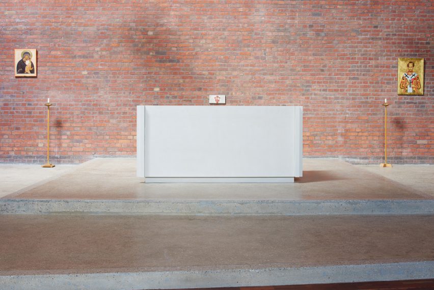 White monolithic altar made of Portland limestone in a red brick walled church