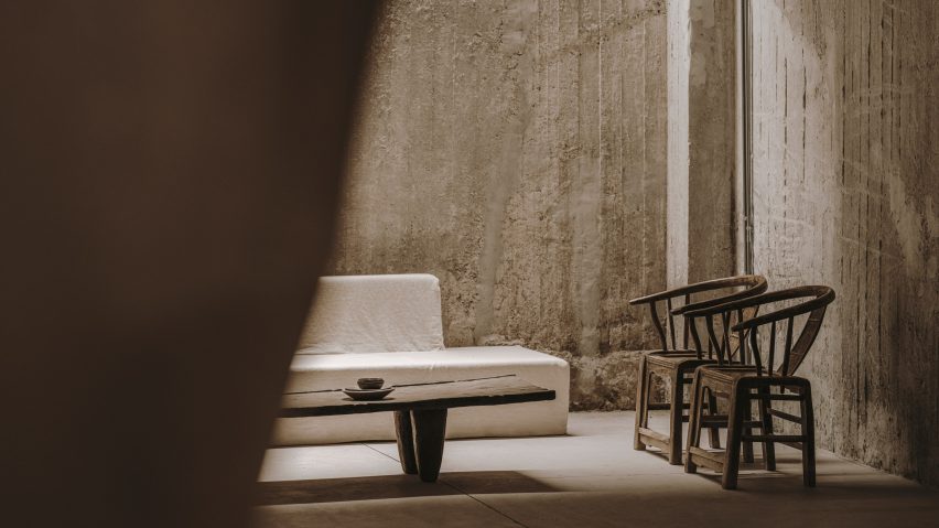 White couch next to wooden table and two armchairs in front of concrete walls in 10AM Lofts event space in Athens by Studio Andrew Trotter