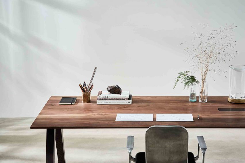 A photograph of the Benchmark wooden desk with plants and stationary upon it