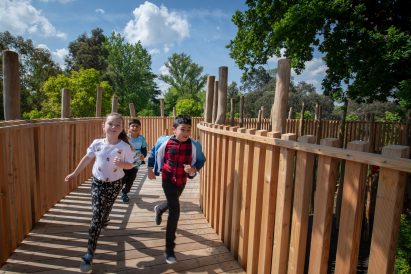 A photograph of children running around one of Kew Garden's treehouses