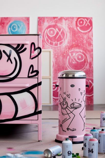 Armour pink kitchen and pedal bin in an artist's studio with spray paint cans scattered