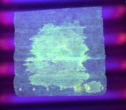 A face mask glowing under ultraviolet light showing coronavirus