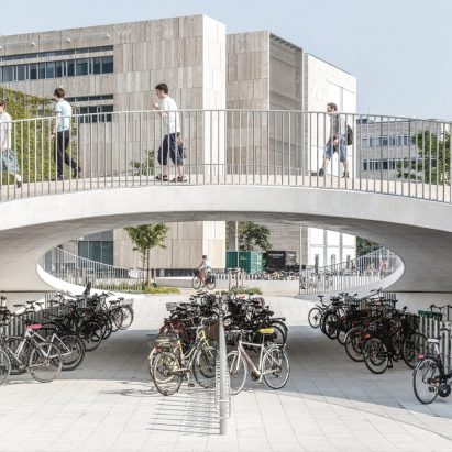 Karen Blixens Plads in Copenhagen by Cobe with bicycle storage and pedestrians passing over a bridge as photographed by Rasmus Hjortshøj illustrating EC proposal on cycling and walking infrastructure