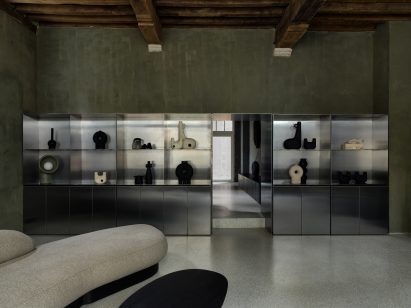 Stainless steel shelving unit housing ceramics in green-painted room in Faina Gallery in Antwerp