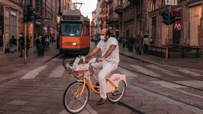 Man cycling in front of a tram in Milan, illustrating a news story about the planned Cambio cycling network in Milan