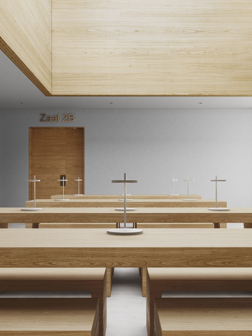 Tilburg University study area with long timber benches and seats under a large wood-framed skylight with cross-shaped lamps on the benches