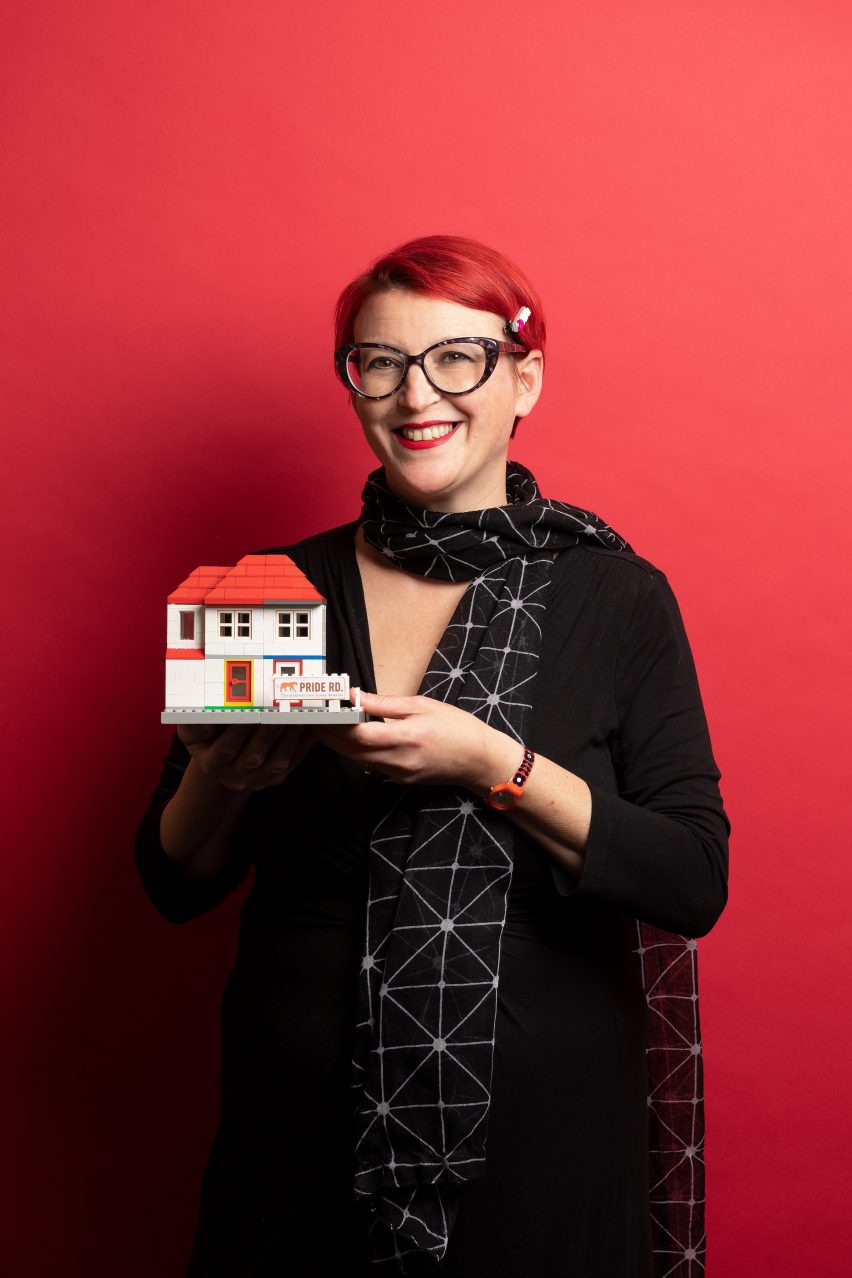 Portrait of Pride Road Architecture founder Lisa Raynes holding a Lego house