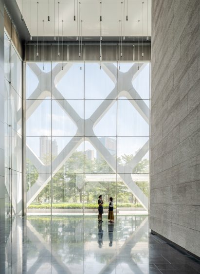 Lobby of SOM's Shenzhen bank building with stone-clad walls on one side and rain-curtain feature in the foreground and exterior diagrid structure visible behind it