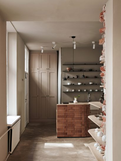 Kitchen of teahouse designed by Yatofu with brick counter and tea paraphernalia displayed on steel shelves