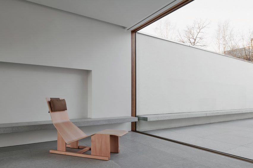 Wooden chaise lounge by Massproductions in front of a large glass sliding door