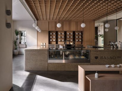Chunky stone counter under a coffered oak ceiling in Xiamen teahouse designed by Norm Architects