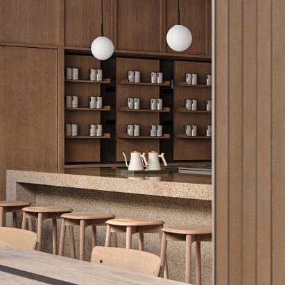 Speckled stone counter surrounded by wooden stools in interior of Basao Tea store in Xiamen, China designed by Norm Architects