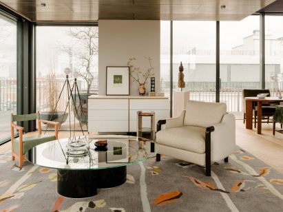 Living room inside Berlin apartment designed by Gisbert Poppler with a grey patterned rug and two armchairs around a glass table