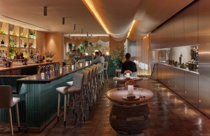 Lounge of Casa Dani restaurant with green marble bar and stainless steel window into kitchen