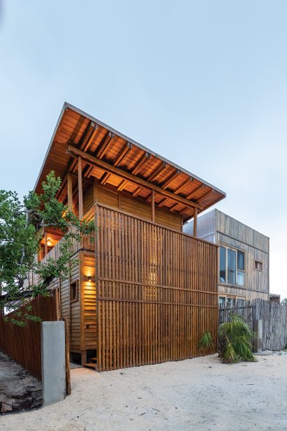 Casa Numa by RED Arquitectos with warm light shining through the exterior lattice at dusk