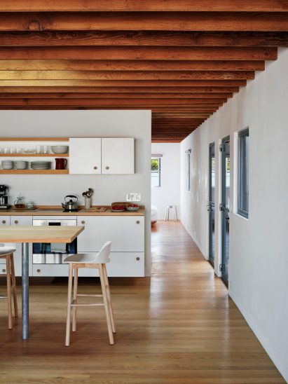 Upstairs guest accommodation area at Emeco House featuring a kitchen with white timber cabinetry and and a high dining table