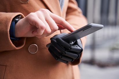 A woman holidng a phone with an prosthetic hand