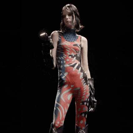 Model scrolling through her phone in a op-art print cat suit