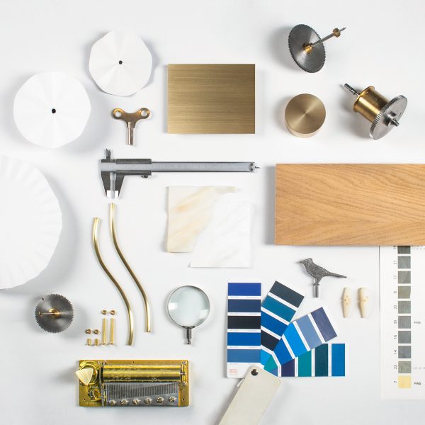 A collection of materials displayed on a white table, include blue paint swatches, wood and metal components