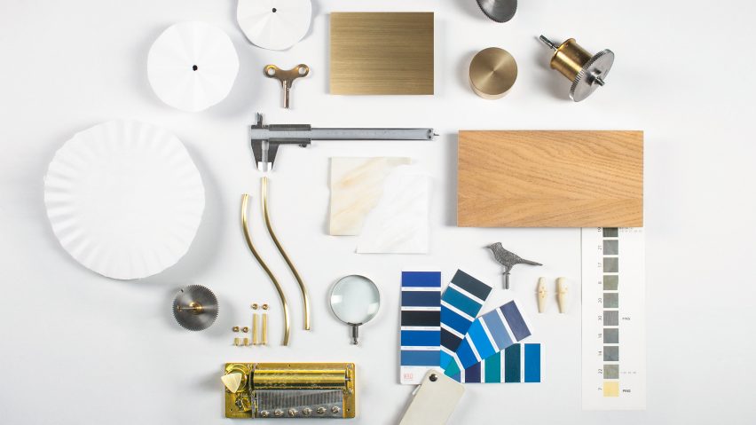 A collection of materials displayed on a white table, include blue paint swatches, wood and metal components