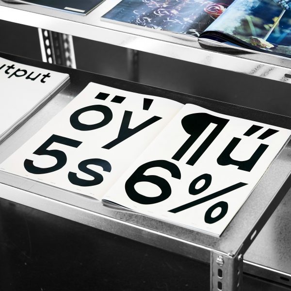 Magazine with large black type printed on white paper laid open on a metal table