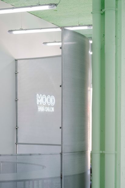 Perforated steel screen in front of neon sign saying Mood hair salon