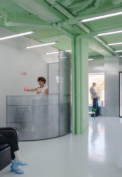 Man holding out a shampoo bottle behind a perforated steel screen in interior by Casa Antillon