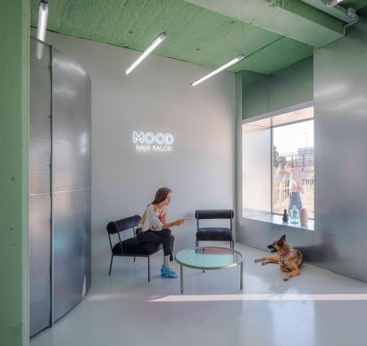 Woman and dog in waiting room of Mood hair salon with black armchairs and round metallic table