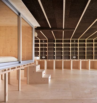 Cork and wood storage wall behind stairs leading up to a bedroom on stilts