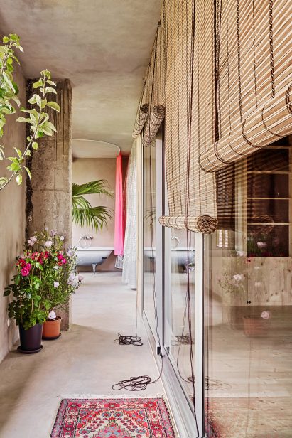 Plant-filled terrace next to wall of glazing leading to an outdoor bath tub