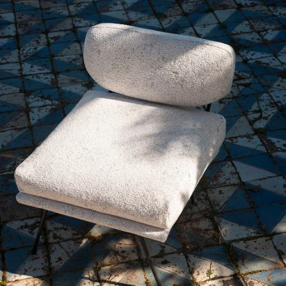 White Textures fabric used as upholstery on a low chair by Dedar