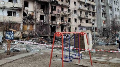 Red swing set in front of a Kyiv building damaged during the Russian invasion of Ukraine