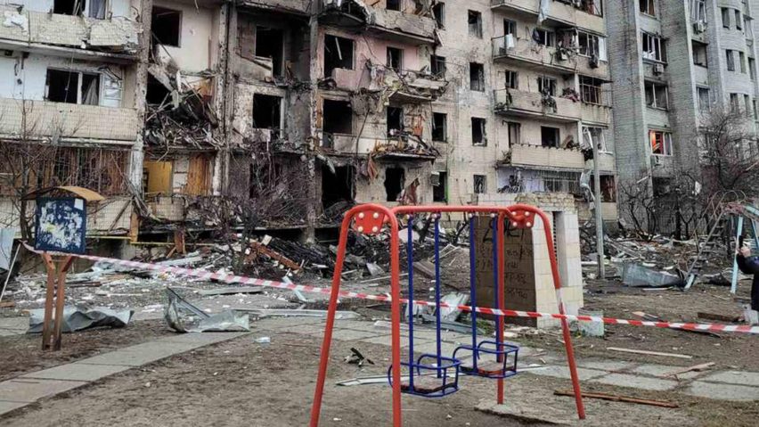 Red swing set in front of a Kyiv building damaged during the Russian invasion of Ukraine