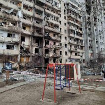 Red swing set in front of a Kyiv building damaged during the Russian invasion of Ukraine