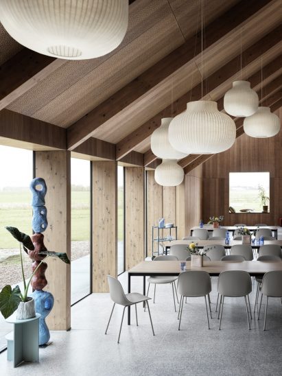 A group of Muuto Fiber Chairs in grey surround an oak veneer table in a minimalist interior